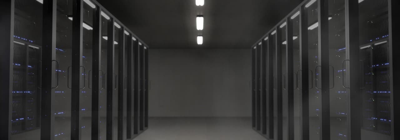 A dark server room with rows of equipment lit by small LEDs