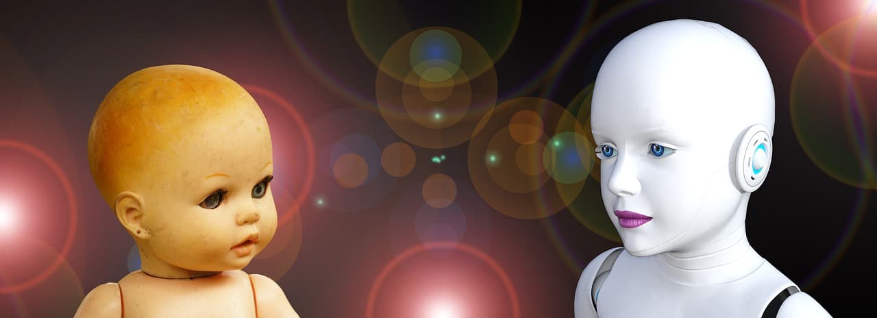 An old baby doll head facing a white android head against a dark background with coloured bokeh circles