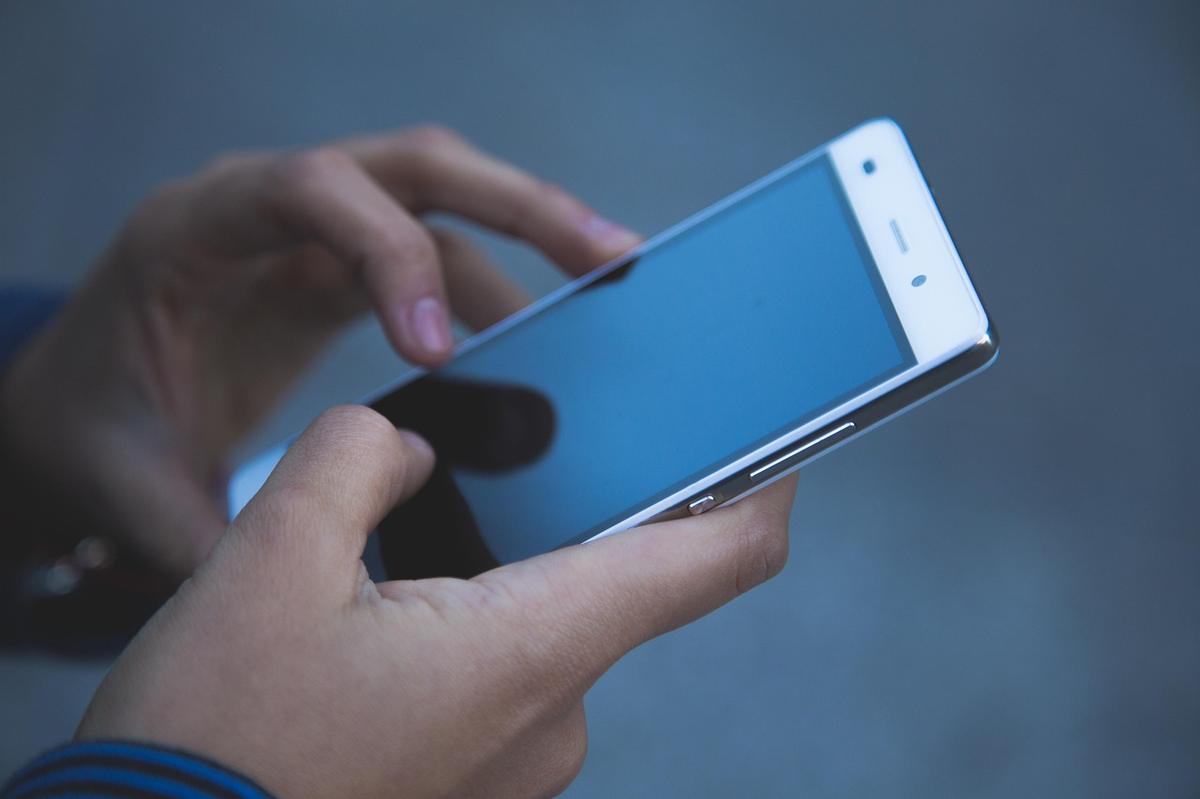 A person's hands using a smartphone, tapping the screen