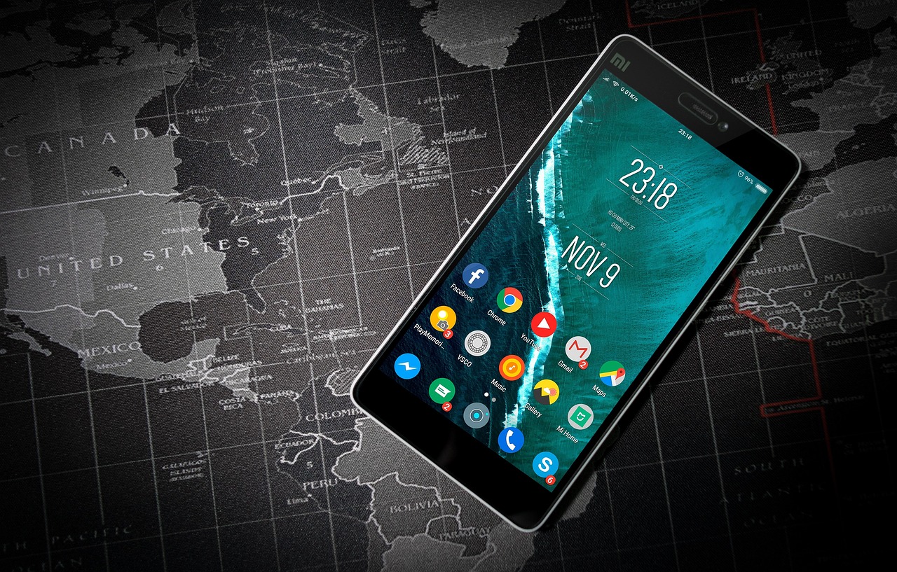 Una pantalla de inicio de un teléfono Android llena de iconos de apps, sobre un mapamundi impreso - tanto ChatGPT como Gemini ofrecen apps móviles que puedes usar en cualquier lugar.