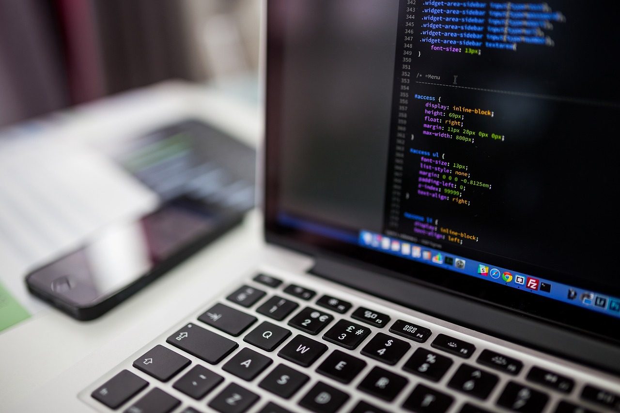 Un portátil mostrando código CSS en un editor, con un smartphone sobre el escritorio