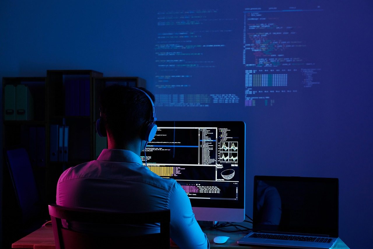 Um desenvolvedor a trabalhar numa secretária com pouca luz com um editor de código aberto no ecrã